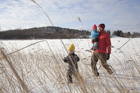 父亲带着两个儿子走在雪地上图片
