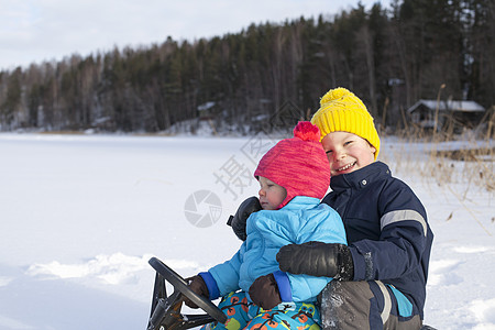 两个小孩在雪地上玩雪橇图片