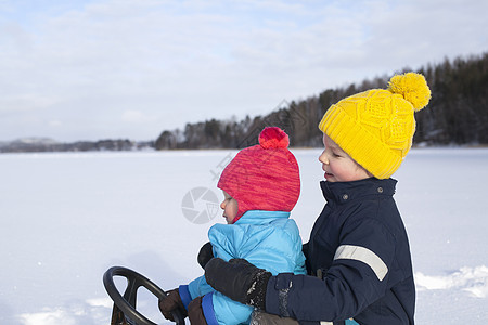 两个小孩在雪地上玩雪橇图片