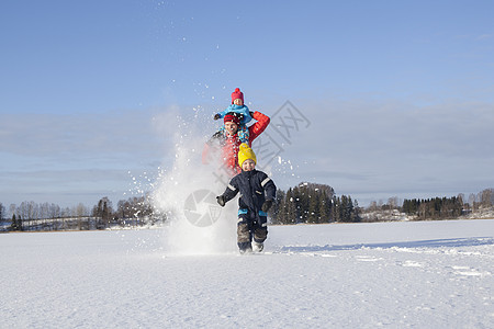 父亲和两个孩子在雪地里玩耍图片