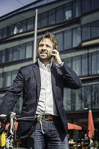 城里骑自行车打智能电话的商人图片