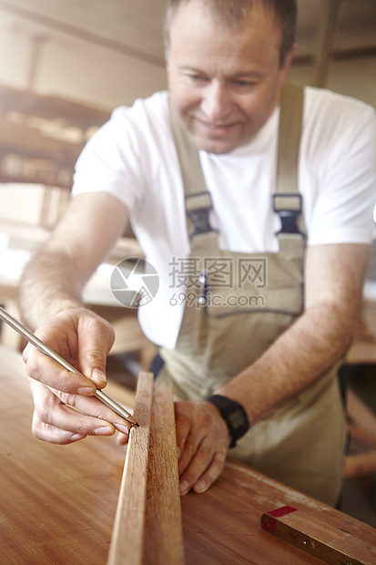 男木匠在工作场所用铅笔在木材上打标记图片