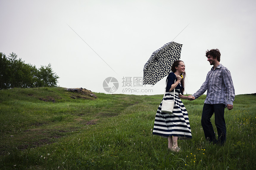 一对夫妇站在野外手牵手拿着雨伞图片
