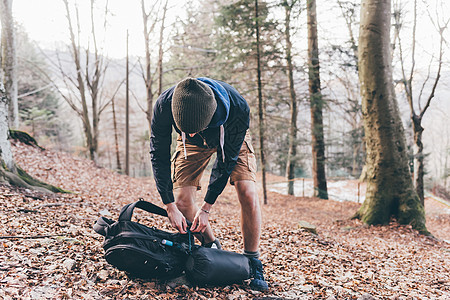 意大利圣普里莫山森林里年轻的男徒步旅行者打开背包图片