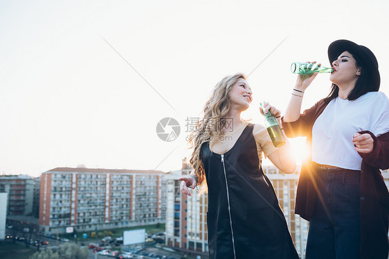 两个女青年在屋顶喝啤酒图片