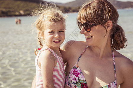 母亲和女儿在海滩上微笑的肖像图片