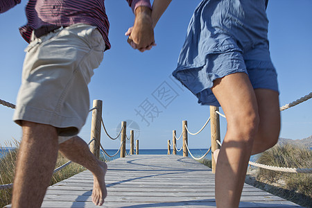 夫妻在海边栈道上笑着奔跑图片