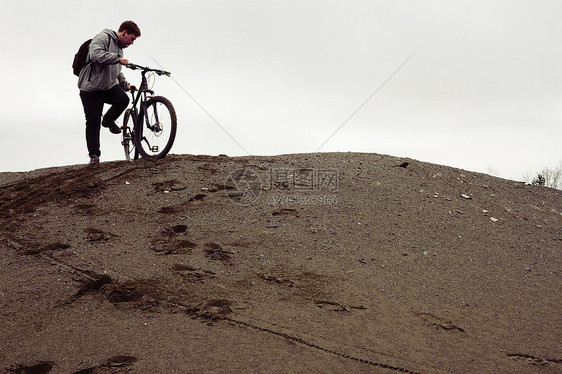 年轻的男山骑自行车者准备从采石山骑自行车下去图片