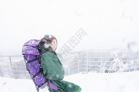 在雪暴中走在山上女徒步旅行者侧身图片