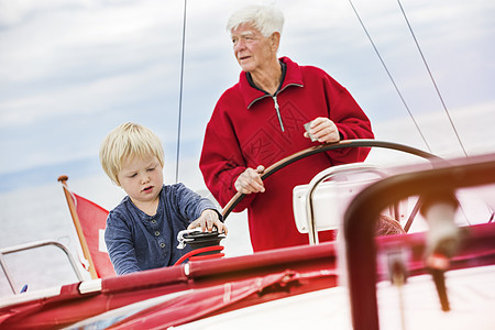 年轻男孩与曾祖父一起乘帆船图片