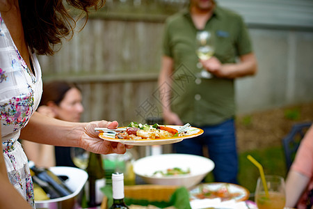 花园派对上持有食品盘子的妇女图片