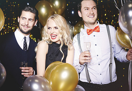 在派对上有三个人被气球包围拿着香槟杯的肖像图片