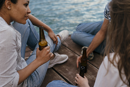 三个朋友在码头拿着啤酒放松图片