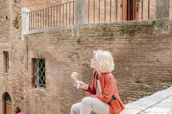 意大利托斯卡纳锡耶州市在楼梯上吃冰淇淋的妇女图片