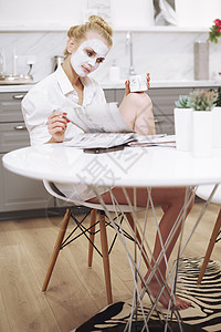 坐在餐桌旁看书杂志上戴面罩的妇女图片