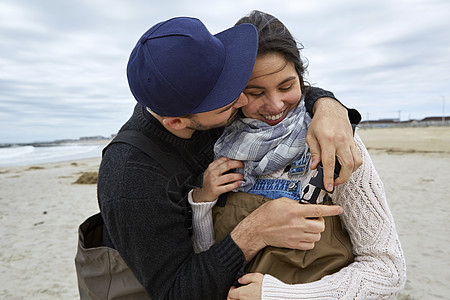 浪漫的年轻情侣在海滩上系着卡扣图片