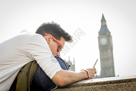 英国伦敦大本钟附近年轻人靠在墙上看着手机图片