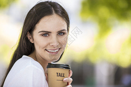 在户外拿着咖啡杯年轻女子的肖像图片