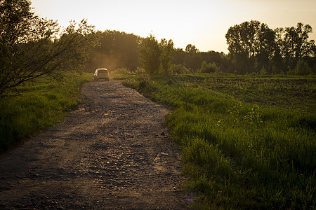 日落时汽车沿灰尘轨道行驶的后视景图片