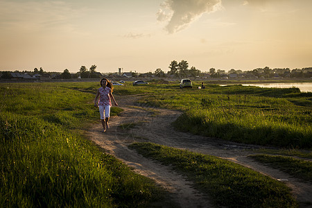 在日落时沿农村泥土轨道运行的孤单少女图片