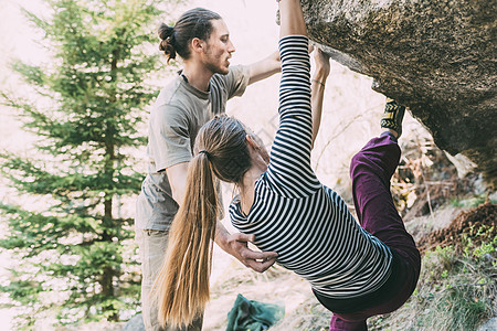 意大利隆巴迪支持妇女攀岩巨石的年轻男师图片