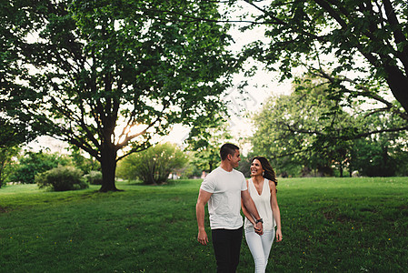 浪漫的年轻夫妇在公园中手牵漫步图片