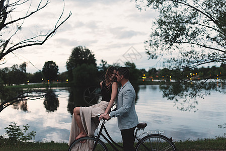 吉卜赛年轻夫妇骑自行车在黄昏的湖边互相看望着对方图片