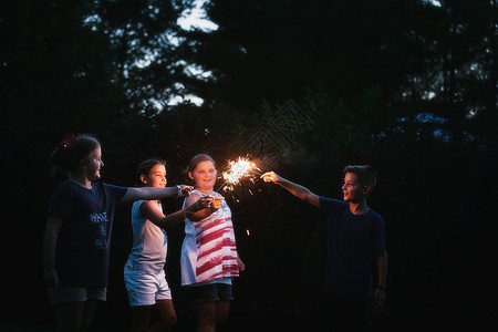美国独立日当天晚上男孩和三个女一起点燃火花图片