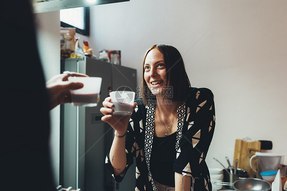 年轻女人和男朋友在厨房里举起咖啡吐司图片