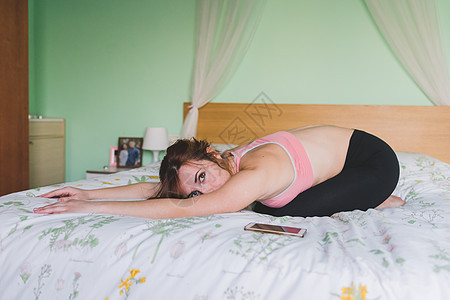 做瑜伽的年轻女子在床上弯腰图片