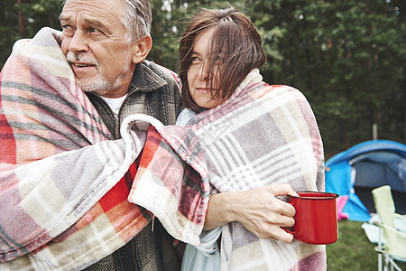 一对成熟夫妇用毛毯包着站在帐篷旁边图片