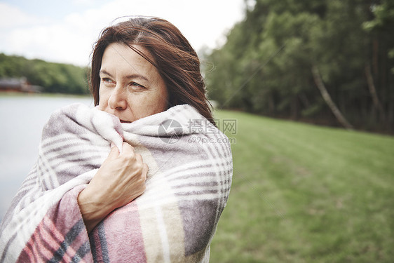 包着毯子女人在河边远望图片