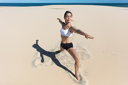 女人在沙滩手臂上张开柔瑜伽的伸展姿势图片