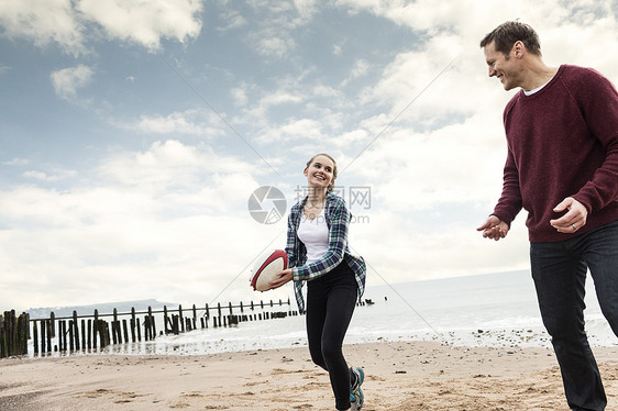 父亲和女儿在海滩玩橄榄球图片