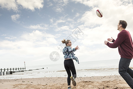 父亲和女儿在海滩玩橄榄球图片