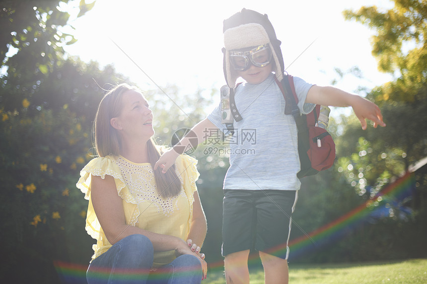 长着儿子的成人假装是飞行员手臂张开在日光花园图片