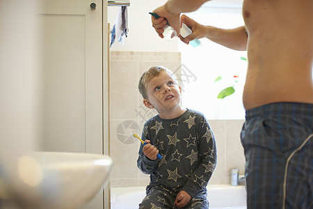 男孩在洗手间准备和父亲一起刷牙图片