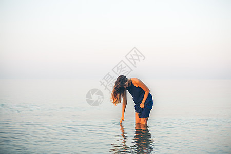 年轻女子在及膝的海水中站在图片