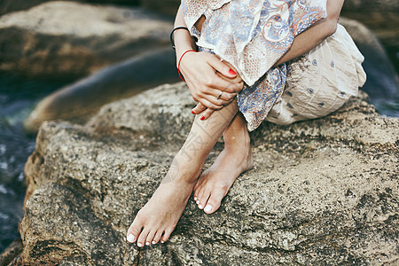 乌克兰敖德萨年轻女子赤脚坐在海岸岩石上的腰部向下视图图片