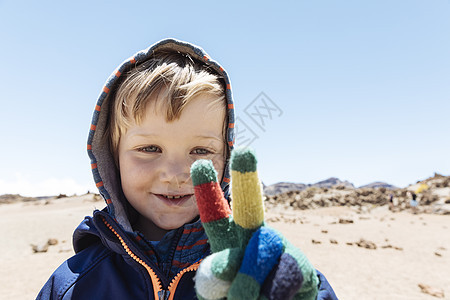 在加那利群岛特纳里费夫的提德山戴着手套做和平标志的可爱男孩肖像图片
