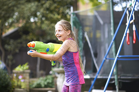 在花园里拿着水枪的湿头发女孩高清图片