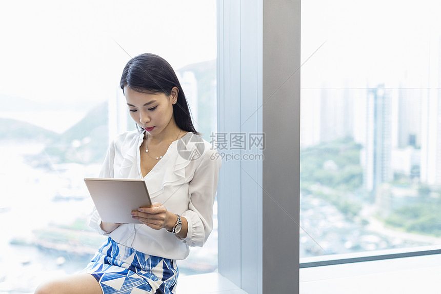 妇女用平板电脑坐在窗台上图片