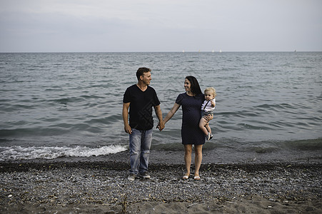 抱着宝宝在海滩边的怀孕夫妇图片