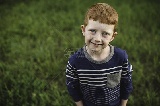 站在草地上的红发男孩图片