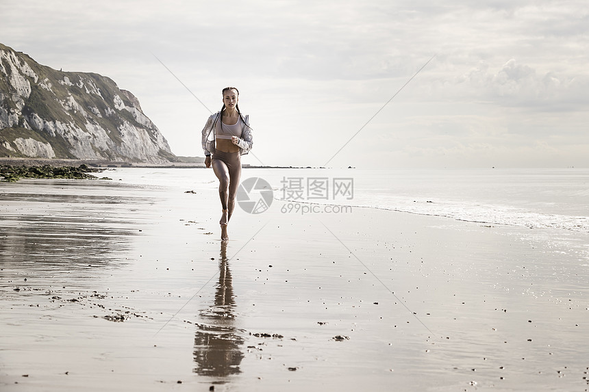 年轻女人赤脚在海滩的上跑步图片