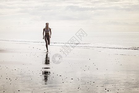 年轻妇女在海滩上奔跑图片