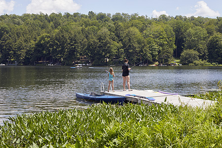 年轻女孩一起在湖边钓鱼图片