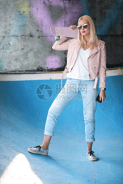 滑板场地上戴着墨镜的金发女滑板运动员图片