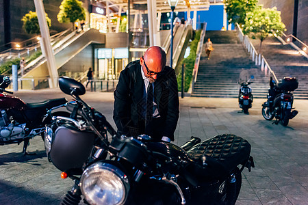 成熟的商人夜间户外活动准备骑摩托车图片