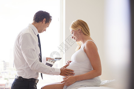 孕妇和丈夫在卧室看超声波照片图片
